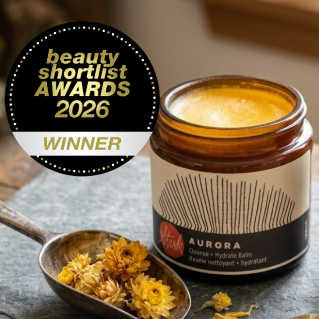 Cosmetic jar and bottle with 'Aurora' and 'Deep Midnight' labels, surrounded by flowers on a textured surface.